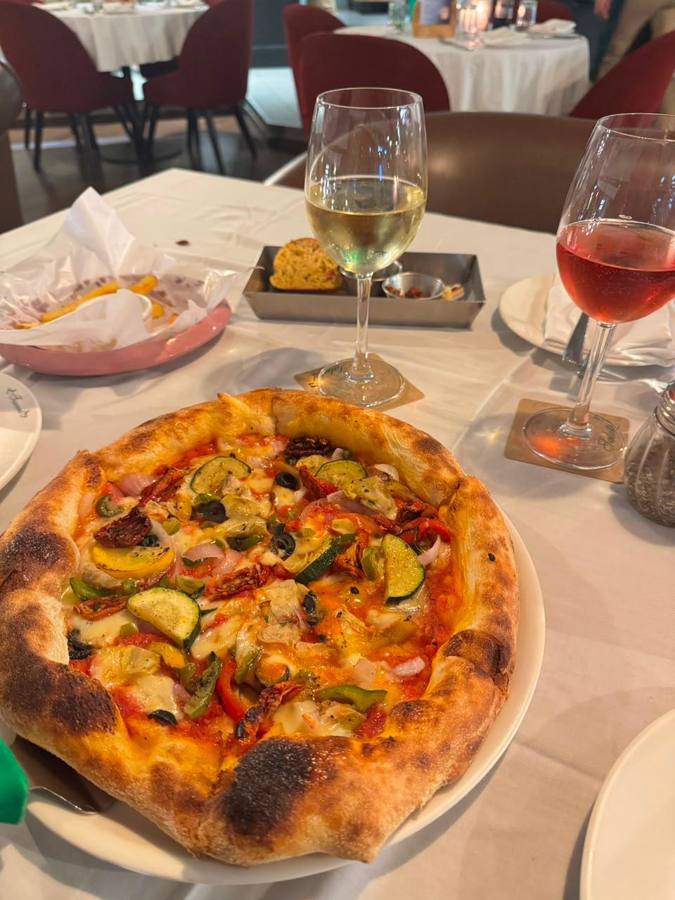 Pizza and two glasses of wine on a white tablecloth