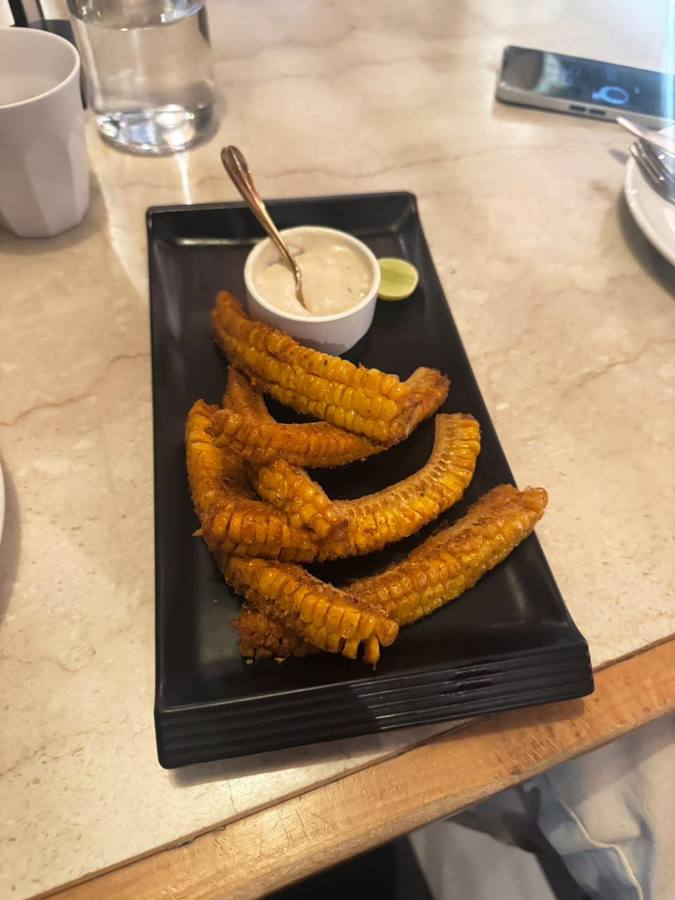Fried corn ribs on a black plate with dip