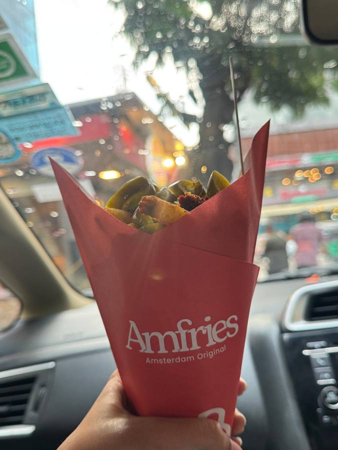 A cone of Amfries with jalapeños, held up in the car