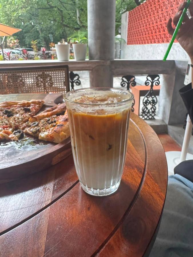 Iced coffee next to pizza on a balcony table